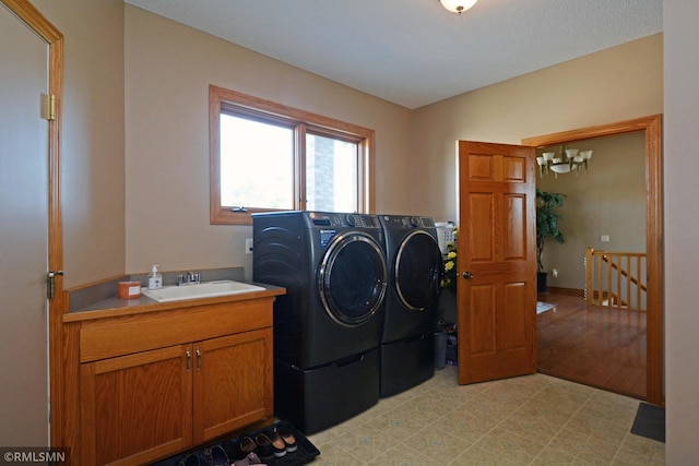 laundry area featuring cabinets, light hardwood / wood-style flooring, sink, and washer and clothes dryer