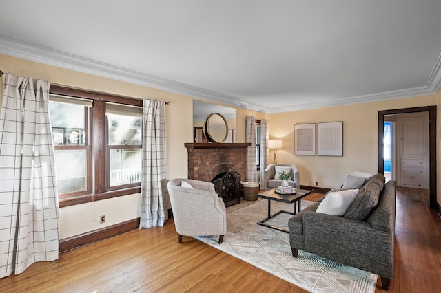 living room with ornamental molding, a brick fireplace, and light wood-type flooring