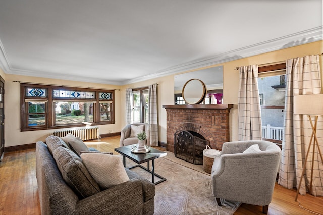 living room with ornamental molding, light hardwood / wood-style flooring, a brick fireplace, and radiator