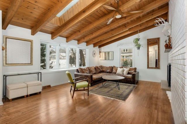 living room with a fireplace, vaulted ceiling with skylight, and wooden ceiling