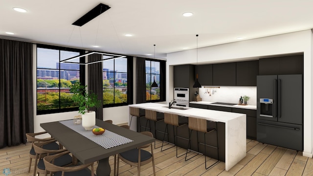 kitchen featuring decorative light fixtures, dark cabinetry, a sink, black appliances, and light countertops