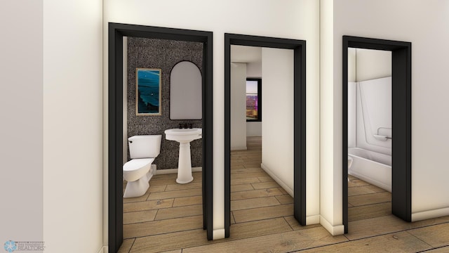 bathroom with toilet, a sink, and wood finish floors