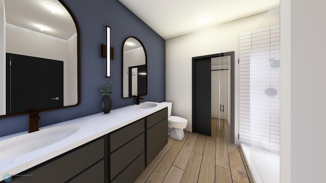 bathroom with a sink, toilet, wood finished floors, double vanity, and tiled shower