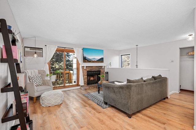 living room with a fireplace, hardwood / wood-style floors, a textured ceiling, and an AC wall unit