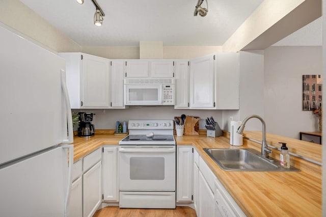 kitchen featuring white appliances, light hardwood / wood-style floors, white cabinetry, and sink