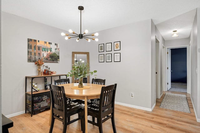 dining room with a textured ceiling, light wood-type flooring, and a notable chandelier