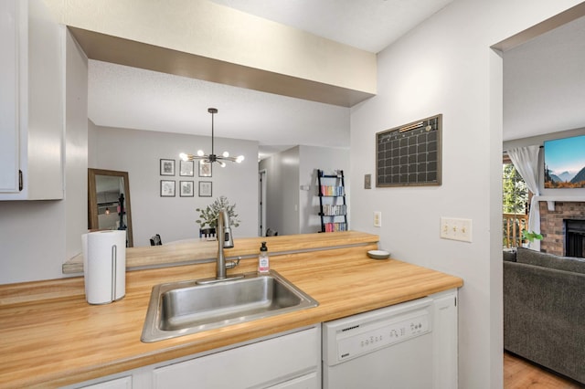 kitchen with dishwasher, white cabinets, a fireplace, and sink