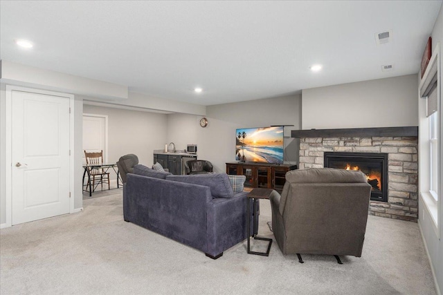 living room with light carpet and a stone fireplace