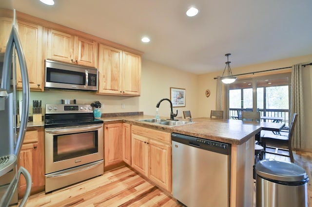 kitchen with stainless steel appliances, sink, light hardwood / wood-style floors, kitchen peninsula, and pendant lighting