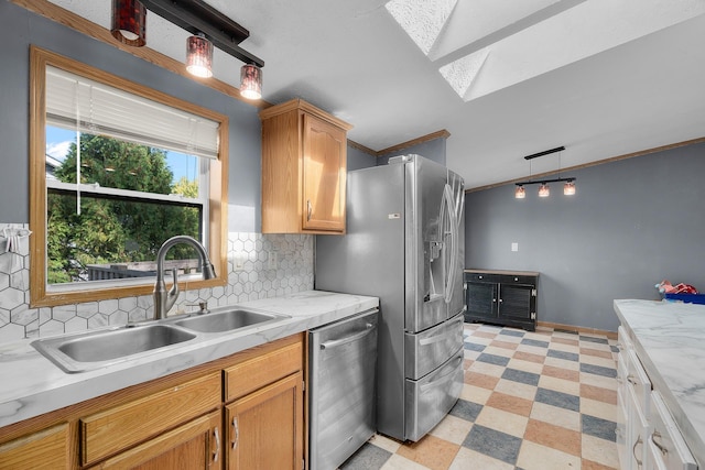 kitchen featuring pendant lighting, backsplash, sink, ornamental molding, and stainless steel appliances