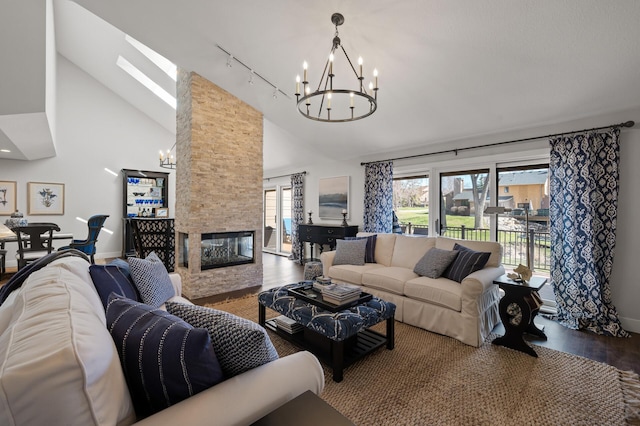 living room with a skylight, wood-type flooring, a stone fireplace, a chandelier, and high vaulted ceiling