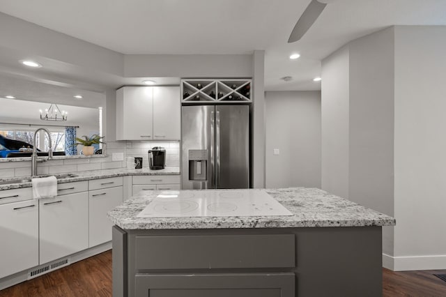 kitchen featuring dark wood-type flooring, a kitchen island, stainless steel fridge, and white cabinetry