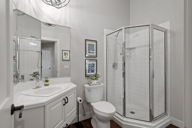 bathroom featuring hardwood / wood-style floors, toilet, vanity, and a shower with shower door