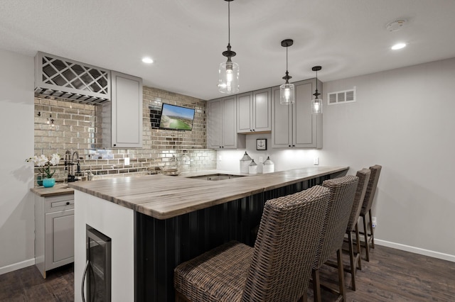 bar with decorative light fixtures, backsplash, beverage cooler, and dark hardwood / wood-style flooring