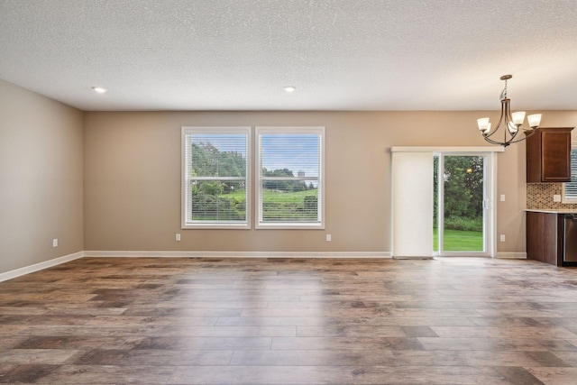 unfurnished living room featuring a textured ceiling, a chandelier, and dark hardwood / wood-style flooring