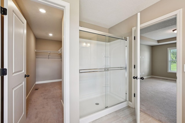 bathroom with a textured ceiling, hardwood / wood-style floors, and a shower with door