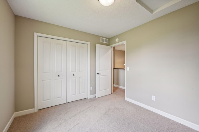 unfurnished bedroom featuring a closet, light colored carpet, and a textured ceiling