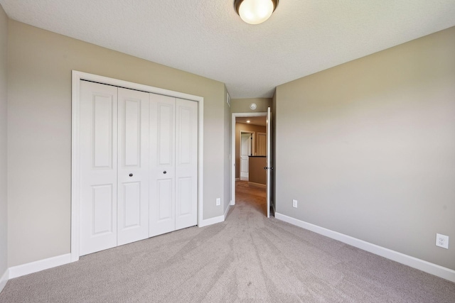 unfurnished bedroom with light carpet, a textured ceiling, and a closet