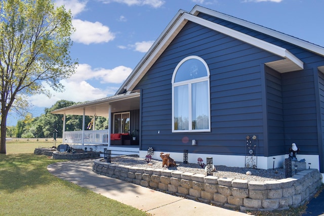 view of home's exterior with covered porch and a lawn