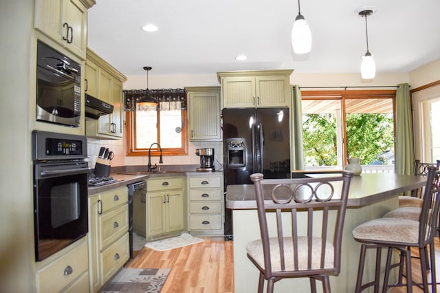 kitchen with light hardwood / wood-style flooring, black appliances, sink, and green cabinetry