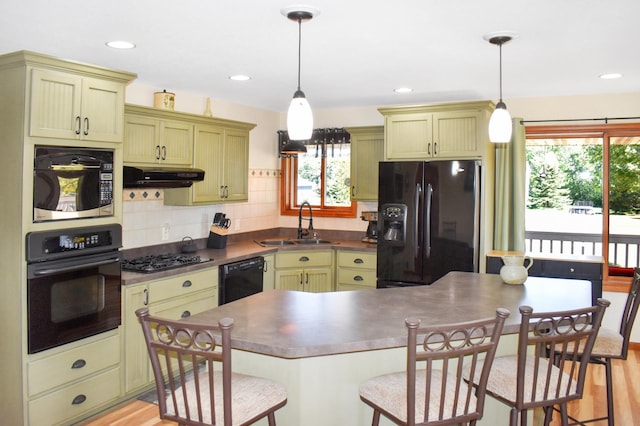 kitchen featuring black appliances, hanging light fixtures, and plenty of natural light