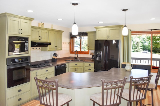 kitchen with a sink, dark countertops, black appliances, under cabinet range hood, and decorative backsplash