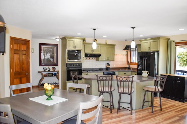 kitchen featuring dark countertops, green cabinets, black appliances, and a sink