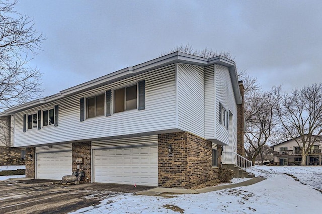 snow covered property with a garage