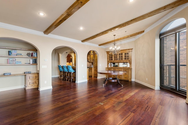 interior space with beam ceiling, built in desk, dark wood-type flooring, a notable chandelier, and crown molding