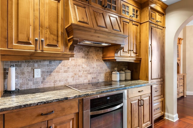 1201 Yale Pl Unit 2303, Minneapolis, MN 55403 - kitchen featuring black electric cooktop, stainless steel oven, arched walkways, and brown cabinets