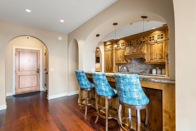 bar featuring dark wood-style floors, recessed lighting, hanging light fixtures, decorative backsplash, and baseboards