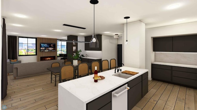 118 Broadway N Unit 602, Fargo, ND 58102 - kitchen featuring light wood-style floors, light countertops, open floor plan, a kitchen island with sink, and decorative light fixtures