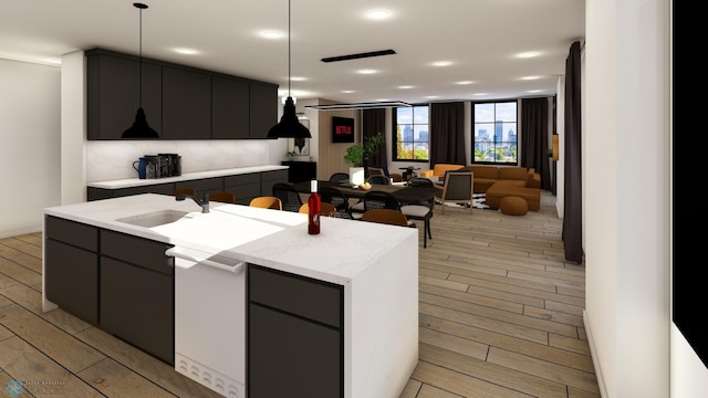 kitchen featuring dishwasher, sink, hanging light fixtures, an island with sink, and light wood-type flooring