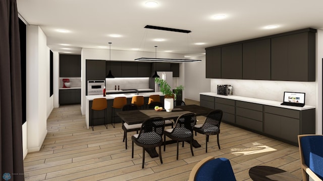 kitchen featuring white oven, a kitchen breakfast bar, hanging light fixtures, decorative backsplash, and light wood-type flooring