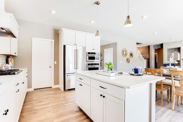 kitchen featuring white cabinets, appliances with stainless steel finishes, hanging light fixtures, and a center island