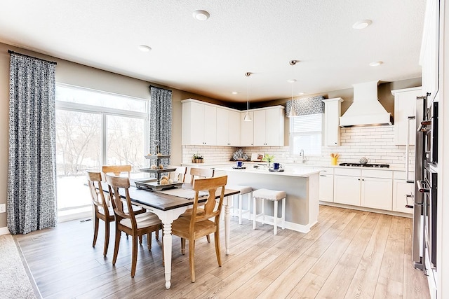 dining space with light hardwood / wood-style flooring, a textured ceiling, and sink