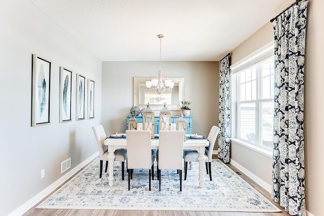 dining room with wood-type flooring, a notable chandelier, and a textured ceiling