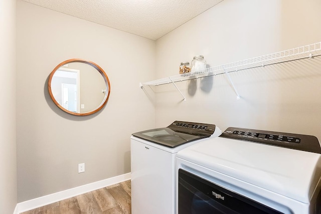 clothes washing area with a textured ceiling, light hardwood / wood-style floors, and washing machine and dryer