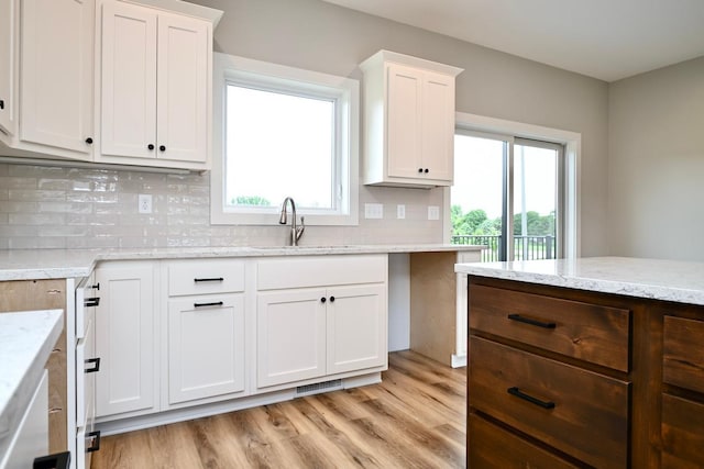 kitchen with light wood-type flooring, a healthy amount of sunlight, and white cabinets