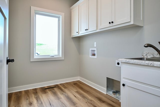 laundry area featuring hookup for an electric dryer, sink, light hardwood / wood-style flooring, washer hookup, and cabinets