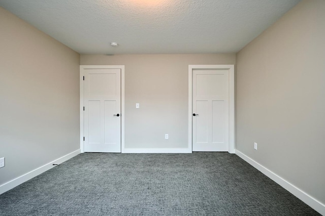 unfurnished bedroom featuring dark carpet and a textured ceiling