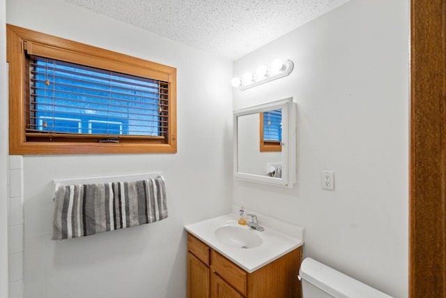 bathroom with a textured ceiling, vanity, and toilet