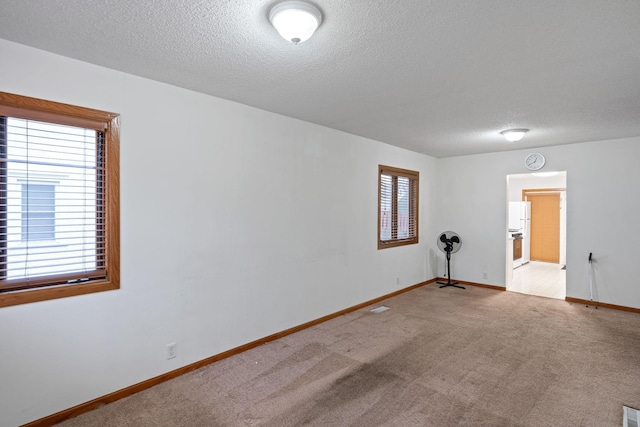 carpeted empty room featuring a textured ceiling