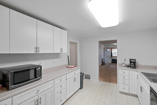 kitchen with white cabinets, stainless steel appliances, and light colored carpet