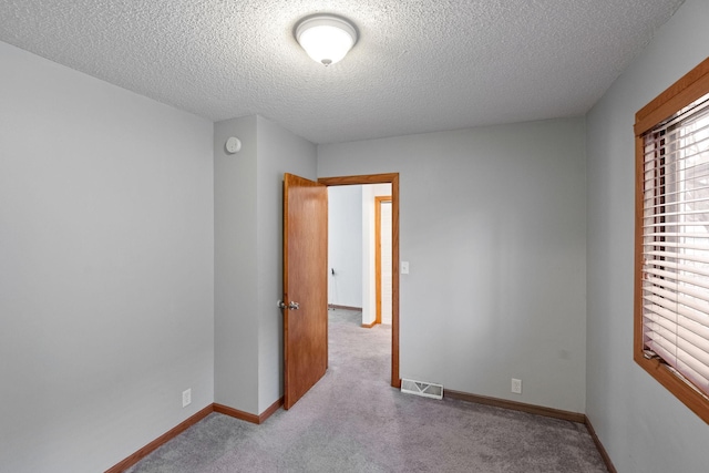 carpeted empty room with a textured ceiling