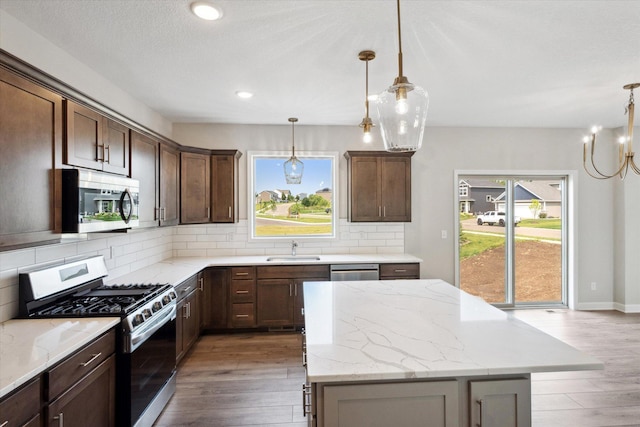 kitchen with sink, light stone countertops, stainless steel appliances, and light wood-type flooring