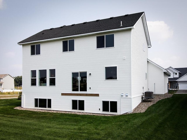 rear view of house with cooling unit and a lawn