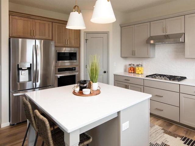 kitchen featuring light hardwood / wood-style floors, appliances with stainless steel finishes, a center island, and hanging light fixtures