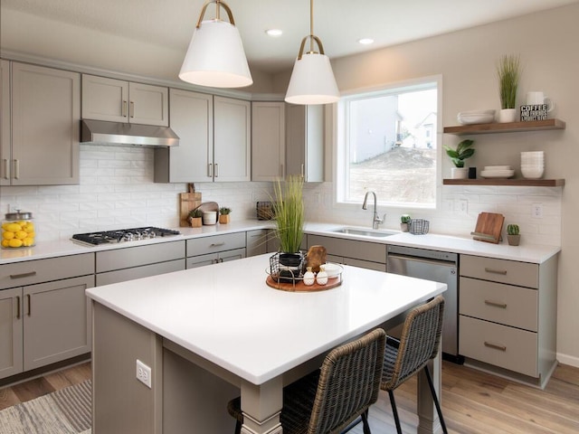 kitchen with appliances with stainless steel finishes, sink, light wood-type flooring, and decorative backsplash