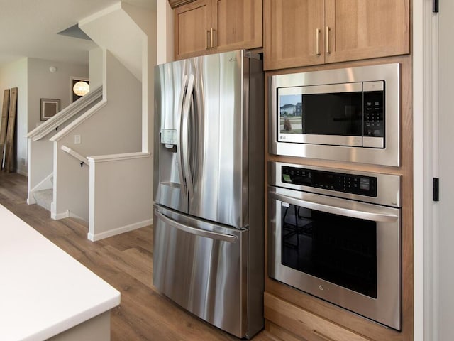 kitchen with appliances with stainless steel finishes, light hardwood / wood-style flooring, and light brown cabinets